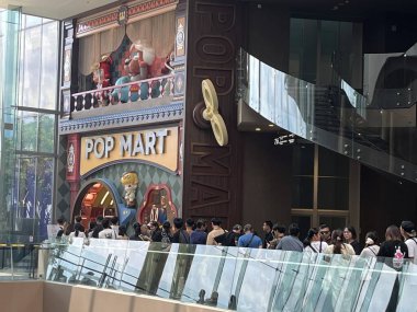 İnsanlar Icon Siyam 'daki dünyanın en büyük Pop Mart mağazasının önünde kuyruğa giriyor, renkli mağaza vitrininde labubu, molly gibi büyük karakterler sergileniyor, güzel tasarım oyuncakları kör kutu koleksiyoncularını çekiyor.