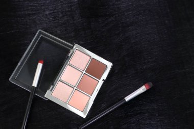 Lüks siyah arka planda makyaj fırçaları olan çıplak göz farı paletinin minimalist düz uzantısı. cilt bakımı için güzellik ve kozmetik konsepti, makyaj dersleri veya ürün reklamcılığı göz farı