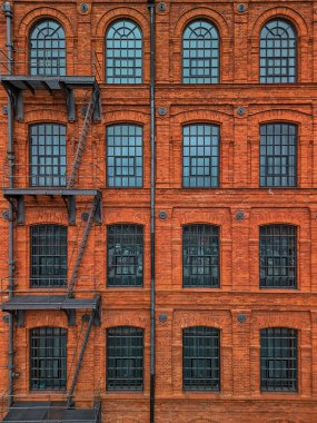 Symmetrical Facade of a Historical Red Brick Industrial Building in Poland. Featuring Multiple Arched Windows and an External Staircase clipart