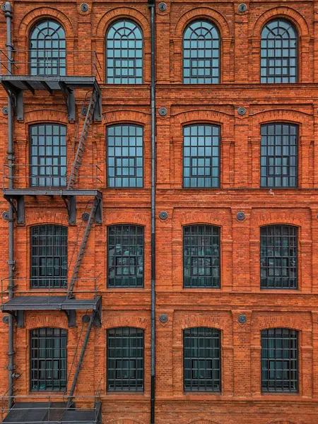Polonya 'daki Tarihi Kırmızı Tuğla Sanayi Binası Simetrik Cephesi. Çoklu Kıvrımlı Pencereler ve Dış Merdiven