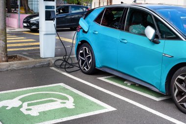 Güneşli bir günde modern bir benzin istasyonunda elektrikli araba şarj ediliyor.