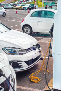Güneşli bir günde modern bir benzin istasyonunda elektrikli araba şarj ediliyor.