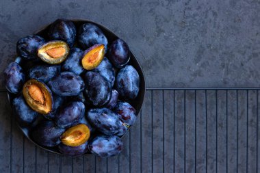 Taze sulu mavi bir bütün ve koyu gri arka planda erikler. Gösterişsiz fotoğraf. Düz kompozisyon. Yukarıdan aşağıya doğru. Yakın plan. Boşluğu kopyala.