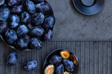 Siyah tabakta taze olgun mavi eriklerin yakın çekimi. Koyu gri arka planda tatlı meyvelerin üst görüntüsü. Gösterişsiz fotoğraf. Düz konum.