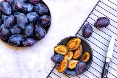 İki tabak bütün ve beyaz mermer arka planda taze olgun mavi erikler. Yukarıdan aşağıya doğru. Yakın plan. Düz konum.