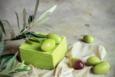 Geleneksel doğal organik zeytin sabunu. Yeşil zeytinli el yapımı sabun ve kırsal arka plandaki dokuda yapraklar. Vücut bakımı onaylandı. Kapatın. Seçici odaklanma. Yumuşak bulanık arkaplan.