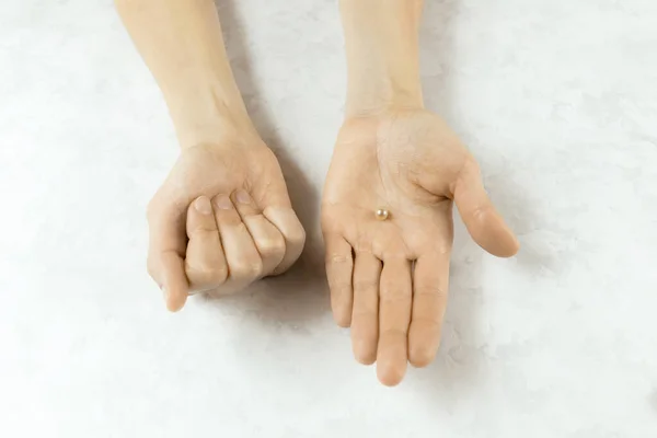 Kobieta Zaciska Pięść Otwiera Dłoń Trzymając Białą Perłę Białym Marmurowym — Zdjęcie stockowe