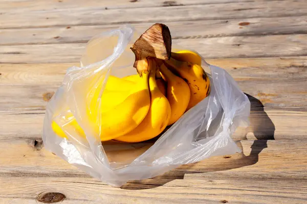 Manojo Plátanos Amarillos Maduros Bolsa Plástico Sobre Superficie Madera Frutas —  Fotos de Stock