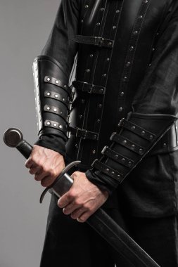 Kara Dul Takan Deri Bileklikli Kılıç Tutan Kişi