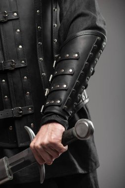 Kara Dul Takan Deri Bileklikli Kılıç Tutan Kişi