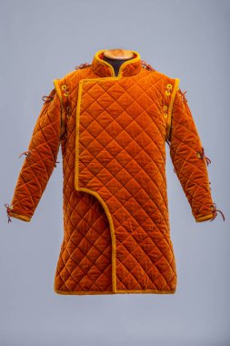 Detaylı İnşaat 'tan Orange Ortaçağ Gambeson. Örtülü zırh ön kapıyı, elmas dikişleri ve kollarda ve omuzlarda kravatları gösteriyor..
