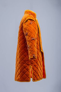 Detaylı İnşaat 'tan Orange Ortaçağ Gambeson. Örtülü zırh ön kapıyı, elmas dikişleri ve kollarda ve omuzlarda kravatları gösteriyor..