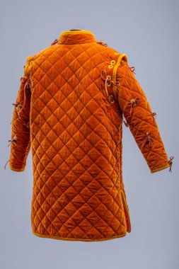 Detaylı İnşaat 'tan Orange Ortaçağ Gambeson. Örtülü zırh ön kapıyı, elmas dikişleri ve kollarda ve omuzlarda kravatları gösteriyor..