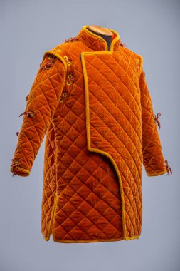 Detaylı İnşaat 'tan Orange Ortaçağ Gambeson. Örtülü zırh ön kapıyı, elmas dikişleri ve kollarda ve omuzlarda kravatları gösteriyor..