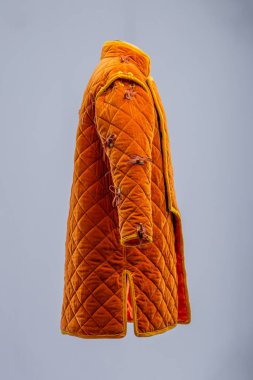Detaylı İnşaat 'tan Orange Ortaçağ Gambeson. Örtülü zırh ön kapıyı, elmas dikişleri ve kollarda ve omuzlarda kravatları gösteriyor..
