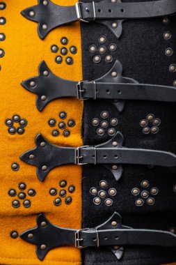 Ortaçağ Brigandine Buckles ve Deri 'nin yakın plan detayları. Parlak sarı ve siyah gövde zırhı üzerindeki karmaşık bağlama sistemi.