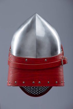 Koruyucu ağ vizörlü modern eskrim kaskı. Parlak gümüş bir miğfer tam bir yüz kafesi içerir ve kırmızı deri kayış ve metal tokayla güvence altına alınır..