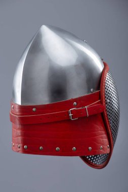 Koruyucu ağ vizörlü modern eskrim kaskı. Parlak gümüş bir miğfer tam bir yüz kafesi içerir ve kırmızı deri kayış ve metal tokayla güvence altına alınır..