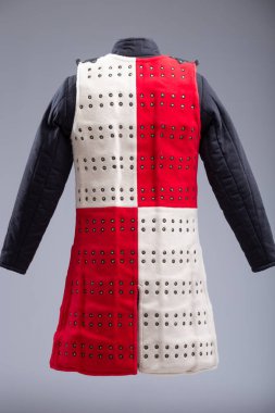 Kırmızı ve Beyaz Brigandine Zırhı, Studs ve Black Straps. Bu resim, biri kırmızı diğeri beyaz olmak üzere iki yarıya bölünmüş bir Brigandine zırhını gösteriyor. Sıraları küçük pirinç renkli çiviler içeriyor ve çoklu siyah ile korunuyor 