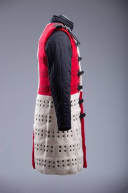 Kırmızı ve Beyaz Brigandine Zırhı, Studs ve Black Straps. Bu resim, biri kırmızı diğeri beyaz olmak üzere iki yarıya bölünmüş bir Brigandine zırhını gösteriyor. Sıraları küçük pirinç renkli çiviler içeriyor ve çoklu siyah ile korunuyor 