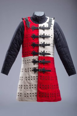Kırmızı ve Beyaz Brigandine Zırhı, Studs ve Black Straps. Bu resim, biri kırmızı diğeri beyaz olmak üzere iki yarıya bölünmüş bir Brigandine zırhını gösteriyor. Sıraları küçük pirinç renkli çiviler içeriyor ve çoklu siyah ile korunuyor 