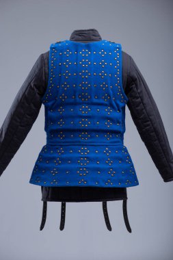 Parlak Mavi Brigandine Zırhı, Studs ve Black Straps. Bu resim parlak mavi bir brigandin zırhı gösteriyor. Sıraları küçük pirinç renkli çiviler ve çoklu siyah deri kayışlar ve gümüş tokalarla korunuyor..
