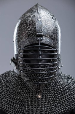 Ribbed Faceplaka ve Zincirli Kask. Bu görüntü koyu, muhtemelen karartılmış bir çeliği, sivri uçlu bir miğferi ve yatay kaburgaları olan belirgin bir yüz plakasını gösteriyor. Kaskın tabanından bir zincirli tasma uzanıyor..