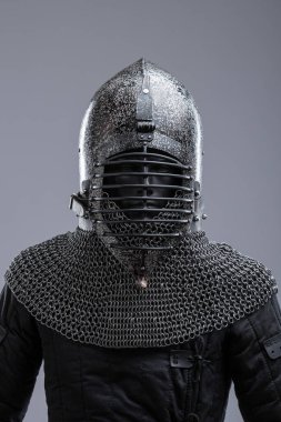 Ribbed Faceplaka ve Zincirli Kask. Bu görüntü koyu, muhtemelen karartılmış bir çeliği, sivri uçlu bir miğferi ve yatay kaburgaları olan belirgin bir yüz plakasını gösteriyor. Kaskın tabanından bir zincirli tasma uzanıyor..