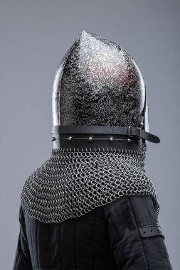 Dark Metal Miğfer, Sivri uçlu ve Faceplakalı. Bu resim, yüzün alt kısmını kaplayan ve görüş için çeşitli yatay yarıklara sahip koyu metal bir miğfer ve bir yüz plakası göstermektedir. Bir zincirli tasma hel 'e bağlıdır.
