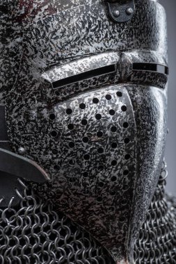 Dark Metal Miğfer, Sivri uçlu ve Faceplakalı. Bu resim, yüzün alt kısmını kaplayan ve görüş için çeşitli yatay yarıklara sahip koyu metal bir miğfer ve bir yüz plakası göstermektedir. Bir zincirli tasma hel 'e bağlıdır.