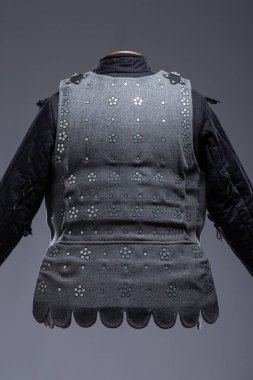 Deri kayışlı gri Ortaçağ Brigandine Zırhı. Bu gri brigandin, üst üste binen metal plakaların kumaş tabanına perçinlenmiş ve deri kayışlarla güvence altına alınmış halidir..