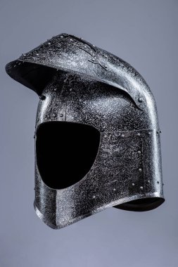 Menteşeli Ortaçağ Şövalyesi Miğferi. Bu resim ortaçağ şövalye miğferini gösteriyor, muhtemelen çelikten yapılmış, yuvarlak bir üst ve menteşeli bir güneşliği var.