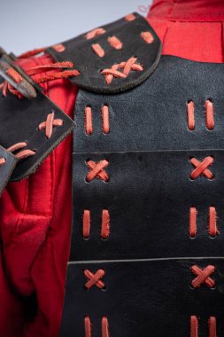 Siyah ve Kırmızı Deri Omuz Zırhı 'nın yakın çekimi. Siyah deri ve zıt kırmızı bağcıklı mankenin omuz zırhının detaylı görüntüsü.