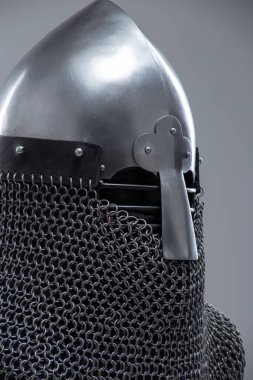 Burun Barı 'ndan Gümüş Norman Miğferi. Bu görüntü, konik şekliyle karakterize edilmiş parlak gümüş bir Norman miğferi ve yüz koruması için ön tarafa uzanan belirgin bir burun barı gösteriyor. Ayrıca altında görünen bir posta kapağı var..