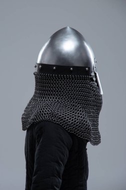 Burun Barı 'ndan Gümüş Norman Miğferi. Bu görüntü, konik şekliyle karakterize edilmiş parlak gümüş bir Norman miğferi ve yüz koruması için ön tarafa uzanan belirgin bir burun barı gösteriyor. Ayrıca altında görünen bir posta kapağı var..