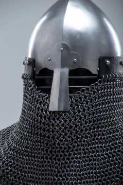 Burun Barı 'ndan Gümüş Norman Miğferi. Bu görüntü, konik şekliyle karakterize edilmiş parlak gümüş bir Norman miğferi ve yüz koruması için ön tarafa uzanan belirgin bir burun barı gösteriyor. Ayrıca altında görünen bir posta kapağı var..