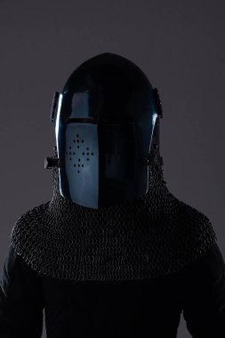 Karanlık Ortaçağ Miğferi ve zincirli tasması. Bu resim siyah, neredeyse siyah, ortaçağ kaskı, delinmiş bir güneşlik, gümüş zincirli tasma ve altında koyu renk bir giysi ile eşleştirilmiş..