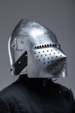 Bir Ortaçağ Şövalyesinin Kaskının Performanslı Kaskı. Bu görüntü, güneşliğinde siyah örtülü bir kişinin giydiği sayısız küçük delikleri olan parlak metal bir miğfere odaklanıyor..