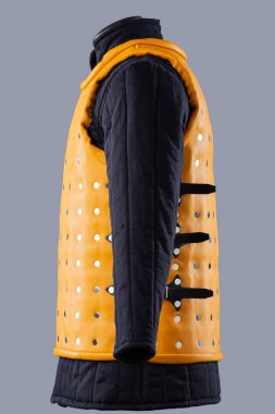 Parlak Sarı Brigandine Zırhı ve Studs. Bu resim parlak sarı bir brigandin zırhı gösteriyor, gümüş sütunlar ve kenarlarında tokalar olan siyah kayışlar var..