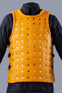 Parlak Sarı Brigandine Zırhı ve Studs. Bu resim parlak sarı bir brigandin zırhı gösteriyor, gümüş sütunlar ve kenarlarında tokalar olan siyah kayışlar var..