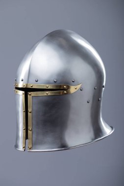 Brass Trim 'li Gümüş Ortaçağ Barbute Miğferi. Bu resim parlak gümüş bir miğfer gösteriyor. Yüzünde belirgin bir T-şekli var. Pirinç süsleme ve perçinlerle vurgulanıyor..