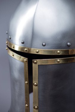 Brass Trim 'li Gümüş Ortaçağ Barbute Miğferi. Bu resim parlak gümüş bir miğfer gösteriyor. Yüzünde belirgin bir T-şekli var. Pirinç süsleme ve perçinlerle vurgulanıyor..