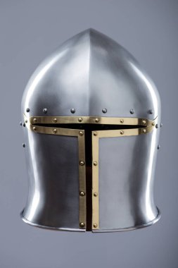 Brass Trim 'li Gümüş Ortaçağ Barbute Miğferi. Bu resim parlak gümüş bir miğfer gösteriyor. Yüzünde belirgin bir T-şekli var. Pirinç süsleme ve perçinlerle vurgulanıyor..