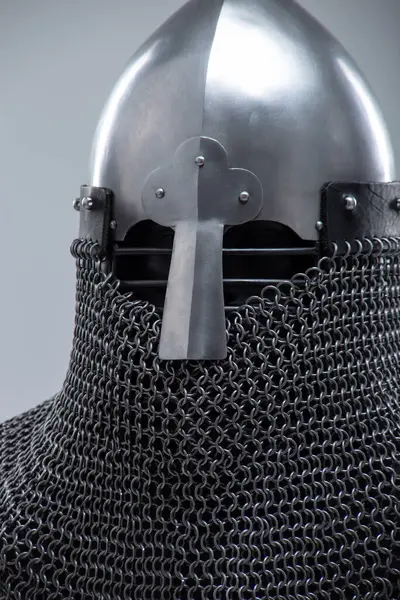 Burun Barı 'ndan Gümüş Norman Miğferi. Bu görüntü, konik şekliyle karakterize edilmiş parlak gümüş bir Norman miğferi ve yüz koruması için ön tarafa uzanan belirgin bir burun barı gösteriyor. Ayrıca altında görünen bir posta kapağı var..