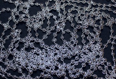 Siyah bir yüzey üzerinde uzun gümüş bir iplik üzerinde parlayan yuvarlak boncuklar.