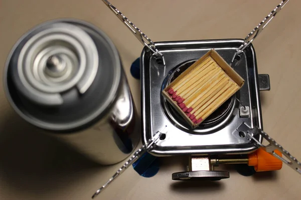 Gas Cartridge Near Portable Stove With Box Of Matches On A Burner