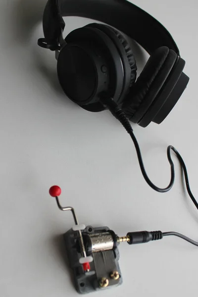 Crankshaft Mini Music Box And Music Headphones On White Surface With Soft Focus