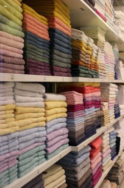 New colored terry towels folded stack on a shelf at fabric store 
