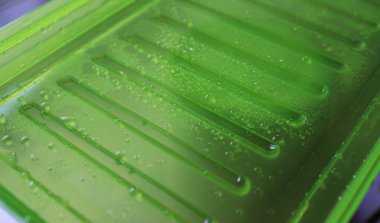 Pattern Of condensation drops and water bulbs on a green plastic close up angle view 