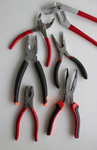 Slip Joint Pliers, Groove Pliers, Needle Nose Pliers And Linesman Pliers Laid Out On White